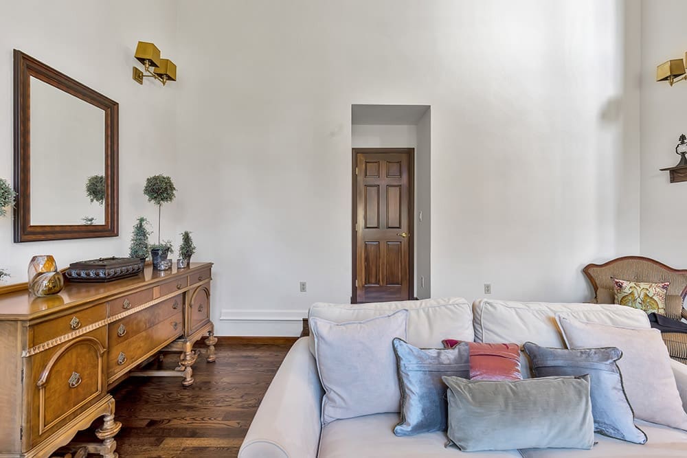 Living room with white sofa, antique wooden console, and dark wooden door.
