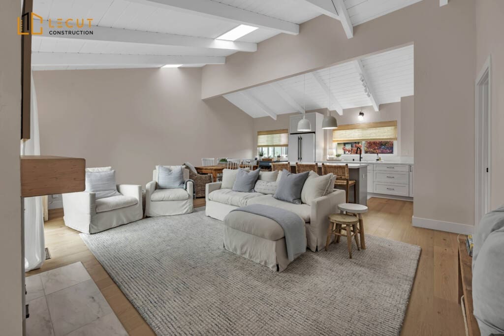 Bright living room with white furniture, light rug, and open-plan kitchen.