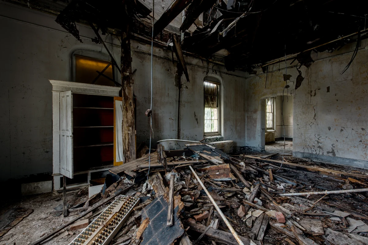 A dilapidated room filled with rubble and debris from a collapsed ceiling.