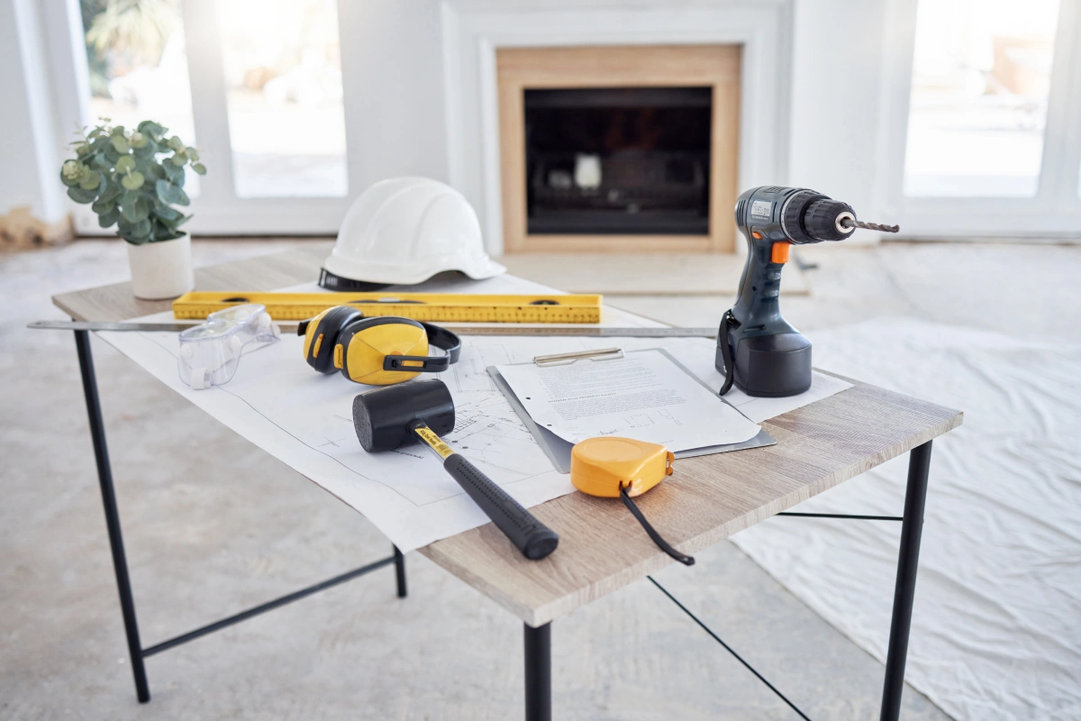 Various construction tools and safety equipment on a desk in a bright room.