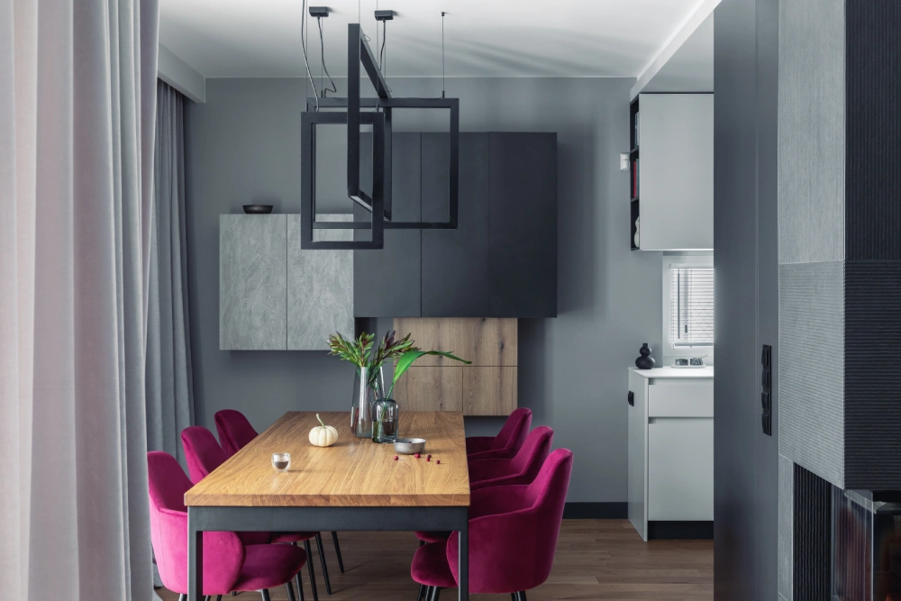 Modern dining room featuring bright magenta chairs around a wooden table.